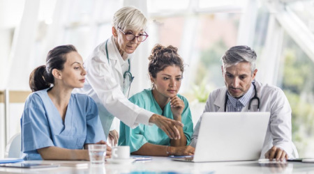 Zdjęcie czterech lekarzy patrzących na ekran laptopa